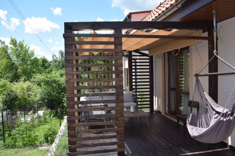 Beigefarbenes Raffrollo, sonnen- und wasserfest, nach Maß auf einer Holzterrasse mit Pergola montiert
