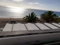 Toldo romano blanco de 2,1x7 m instalado en una estructura de madera en una terraza con vistas al mar