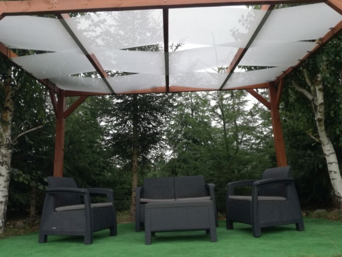 Voile d'ombrage blanc pour pavillon monté sur une pergola en bois au-dessus d'un salon de jardin sur une terrasse