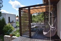 Store bateau de terrasse Premium beige monté sur une pergola en bois au-dessus d'un ensemble de meubles de jardin