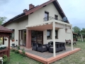 Rulou roman bej pentru terasă 2,5x4 m montat pe o structură deschisă la culoare deasupra mobilierului de grădină de lângă casă