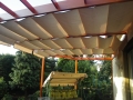 Rulou roman Premium impermeabil pentru terasă în culoarea bej montat sub o pergolă deasupra mobilierului de grădină