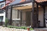Store romain de terrasse Premium imperméable en beige monté sur une pergola en bois avec cordes décoratives