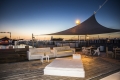 Toldo vela triangular Premium sobre una terraza elegante con muebles de exterior al atardecer