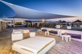 Toldo vela triangular impermeable Premium sobre terraza con muebles de jardín por la noche