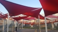 Toldo vela triangular rojo Premium impermeable y para el sol sobre una zona de descanso moderna
