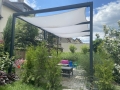 Voile d'ombrage imperméable 3x3 m monté sur une pergola métallique au-dessus d'une terrasse avec salon de jardin