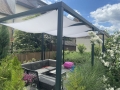 Voile d'ombrage carrée imperméable 3x3 m montée sur une pergola noire au-dessus de meubles de jardin