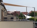 Toldo vela cuadrado impermeable beige 3x3 m instalado como protección solar en el balcón de un piso