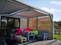 Voile d'ombrage imperméable 3x3 m installée sur une pergola en bois au-dessus d'une terrasse avec meubles en palettes