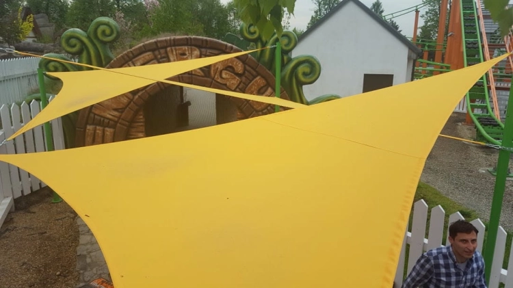 Vodotesná trojuholníková tieniaca plachta 5x5x7 m v žltej farbe namontovaná nad detským ihriskom