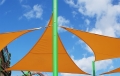 Toldo vela triangular naranja Premium instalado en un poste verde alto