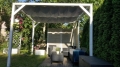 Wasserdichtes und ausziehbares Premium Sonnensegel montiert an einer weißen Pergola-Konstruktion