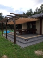 Vela ombreggiante beige impermeabile e retrattile su pergola in legno con terrazza e mobili da giardino