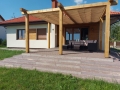 Vela ombreggiante beige impermeabile ed estensibile montata su una pergola in legno sopra la terrazza con mobili da salotto
