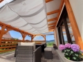 Vela ombreggiante Premium bianca, impermeabile e avvolgibile, montata su una pergola in legno sopra un terrazzo arredato.