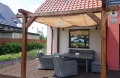 Vela ombreggiante retrattile Premium beige montata su una pergola in legno sopra la terrazza con mobili da salotto