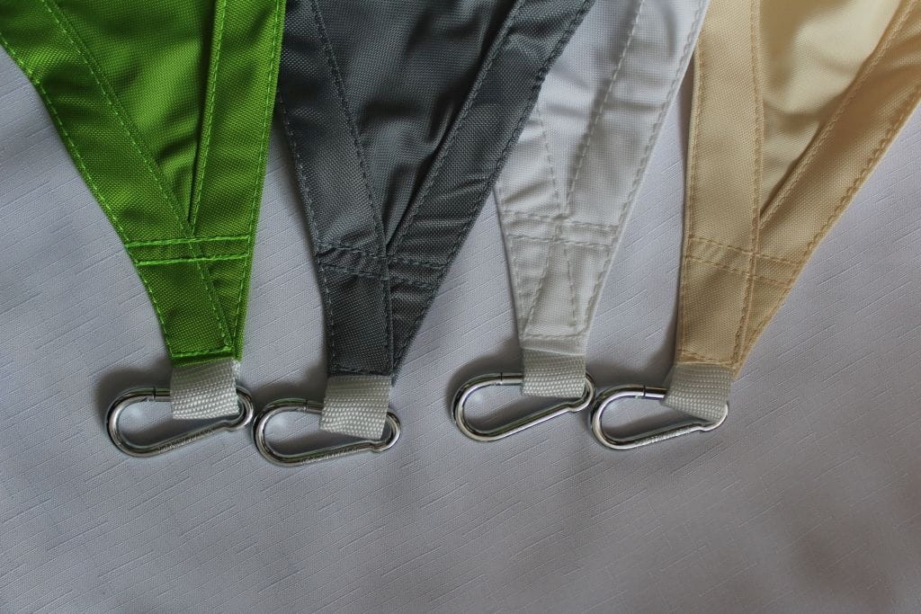 Esquinas de velas de sombra triangulares en colores verde, gris, blanco y beige con mosquetones metálicos