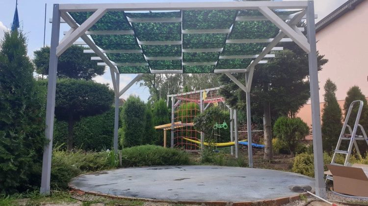 Bande de pavillon imperméable avec imprimé feuilles vertes montée sur une structure de pergola moderne en bois