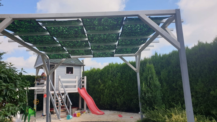 Voile d'ombrage imperméable pour tonnelle avec imprimé feuilles vertes montée sur une pergola en bois dans un jardin