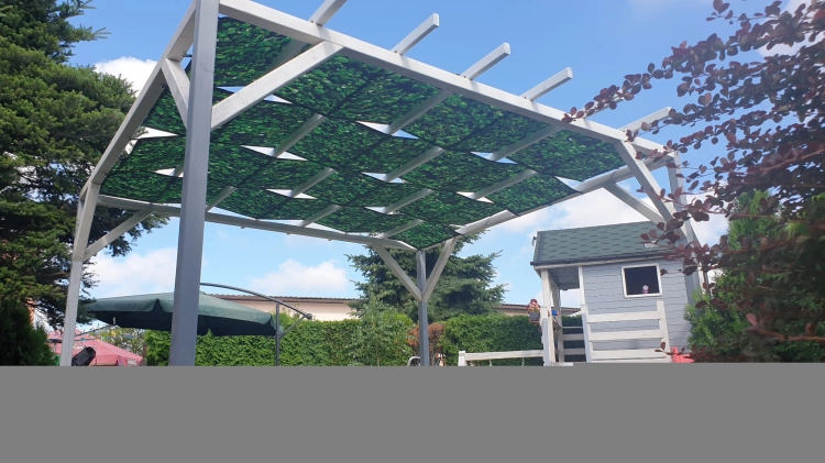 Voilage de jardin imperméable avec motif de feuilles installé sur une pergola en bois.
