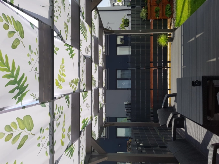 Bande de pavillon imperméable avec imprimé feuilles vertes installée comme pare-soleil sur la structure d'une tonnelle
