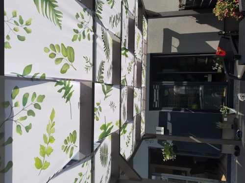 Bande de pavillon imperméable avec imprimé de feuilles vertes montée sur un toit de terrasse en bois