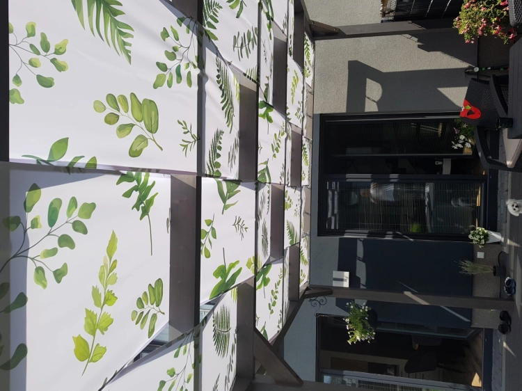 Bande de pavillon imperméable avec imprimé de feuilles vertes montée sur un toit de terrasse en bois