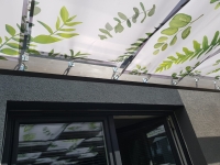 Voile de tonnelle imperméable avec imprimé feuilles montée sur une structure de terrasse en bois