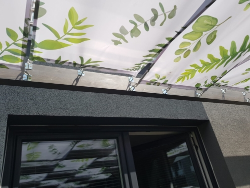 Voile de tonnelle imperméable avec imprimé feuilles montée sur une structure de terrasse en bois