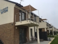 Toldo vela impermeable a medida instalado sobre una terraza y un balcón modernos