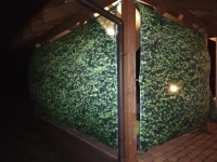 Rideau de jardin vert avec motif de feuilles monté sur un gazebo en bois pour se protéger des voisins