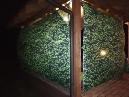 Rideau de jardin vert avec motif de feuilles monté sur un gazebo en bois pour se protéger des voisins