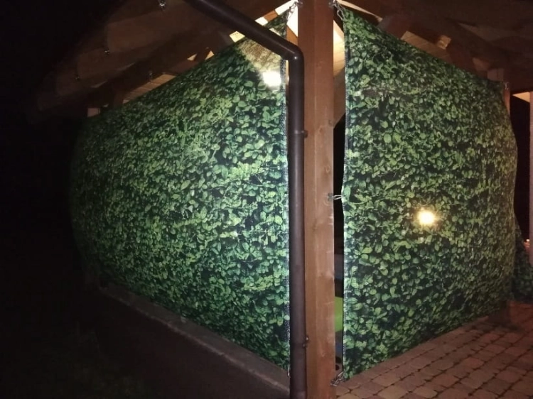 Rideau de jardin vert avec motif de feuilles monté sur un gazebo en bois pour se protéger des voisins