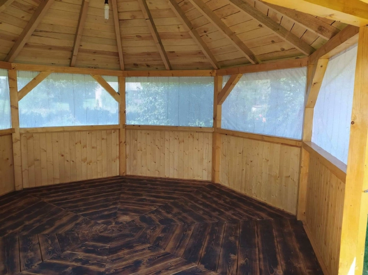 Intérieur d'un pavillon de jardin en bois avec un rideau de jardin sur mesure protégeant les parois ouvertes