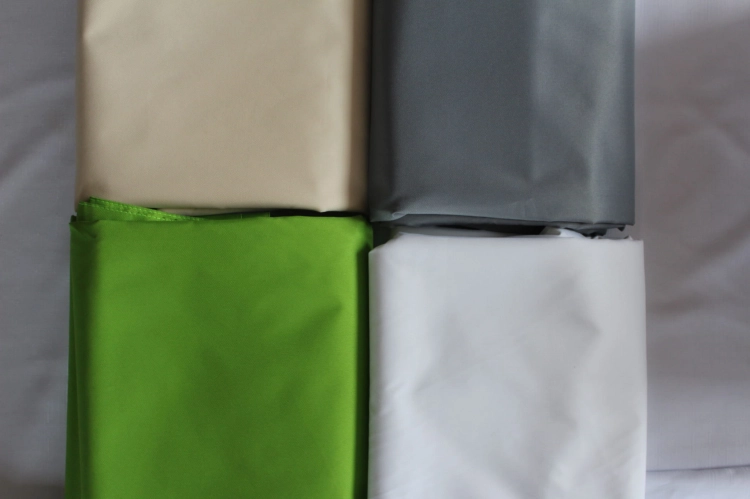 Tissu imperméable pour store romain de terrasse en quatre couleurs : beige, gris, vert et blanc.
