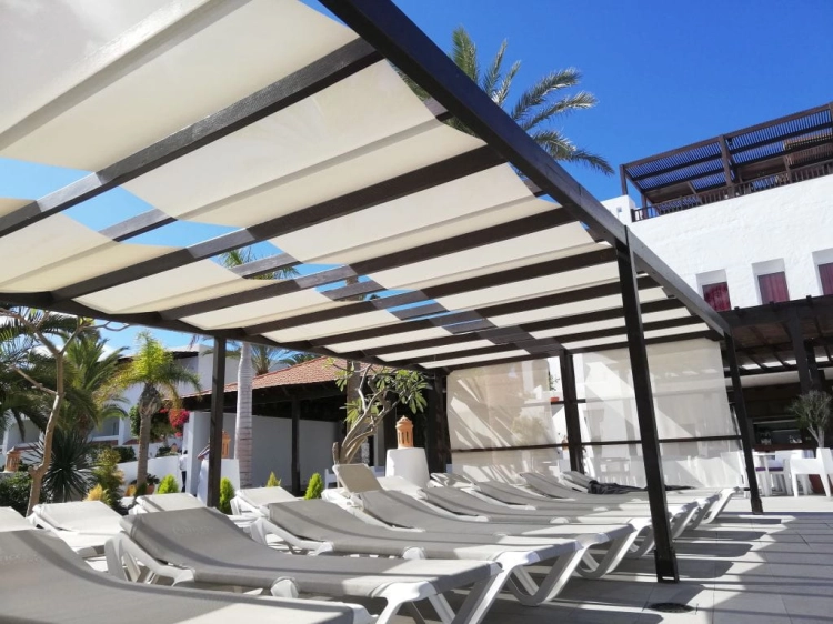 Weißes römisches Sonnensegel auf einer dunklen Konstruktion über Liegestühlen am Pool montiert