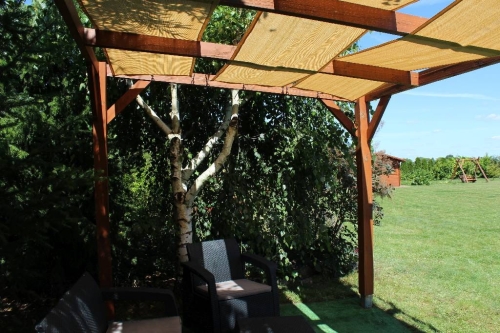 Béžový stínicí pás z HDPE tkaniny o rozměrech 0,4x5 m namontovaný na dřevěné zahradní pergole