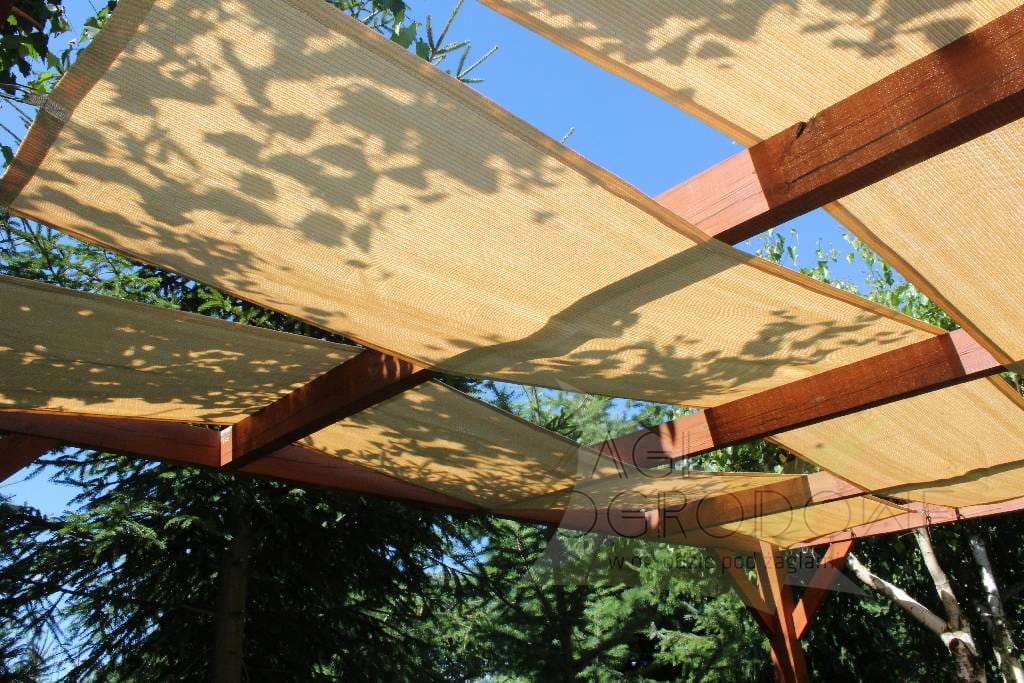 Toldo tipo vela beige de tejido HDPE montado en una estructura de pérgola de madera en el jardín