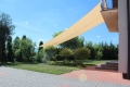 Beige schaduwdoek rechthoekig 4x7 m gemonteerd in de tuin boven een terras van klinkers
