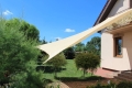 Voile d'ombrage sable 4x7 m en HDPE installée au-dessus de la terrasse et du jardin d'une maison individuelle
