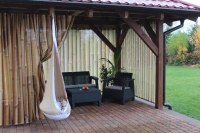 Rideau de jardin avec imprimé tiges de bambou sur une terrasse avec meubles de jardin et fauteuil suspendu cocon