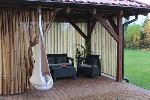 Rideau de jardin avec imprimé tiges de bambou sur une terrasse avec meubles de jardin et fauteuil suspendu cocon