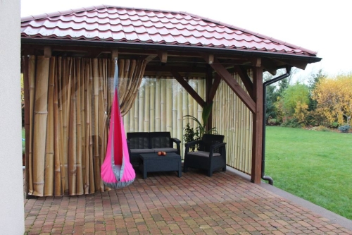 Rideau de jardin avec impression imitation bambou installé dans une tonnelle marron près des meubles de terrasse
