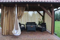 Rideau de jardin avec imprimé de tiges de bambou sur une terrasse avec meubles de jardin et fauteuil suspendu cocon