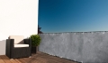Grått balkongskydd med betongmönster, monterat på terrassräcke med fåtölj och krukväxt