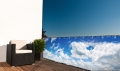 Protezione balcone su misura con stampa di cielo azzurro e nuvole montata sulla ringhiera del terrazzo