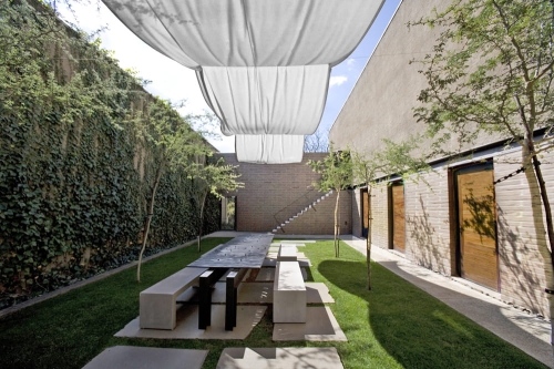Voile romain blanc imperméable sur une terrasse avec table de jardin moderne et mur végétal