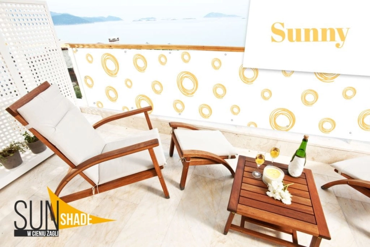 Reklamná balkónová clona Sunny s potlačou žltých kruhov namontovaná na zábradlí terasy so záhradným nábytkom