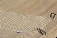Voile d'ombrage couleur sable en maille HDPE avec anneaux de montage en métal visibles et logo Sun nudet